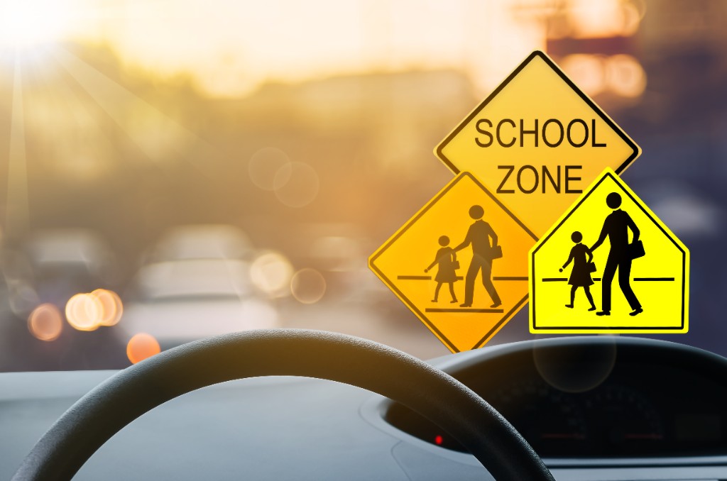 Driver view of Ontario school zone road signs at sunset